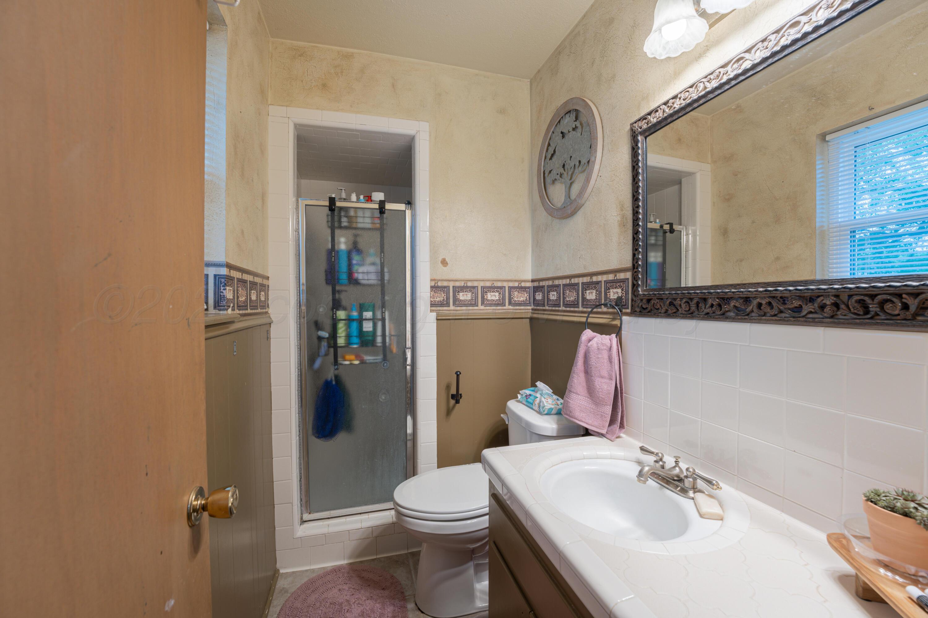 4836 Hillside Road Amarillo, TX 79109 - Photo 16 of 28 a bathroom with a sink vanity granite toilet and a mirror