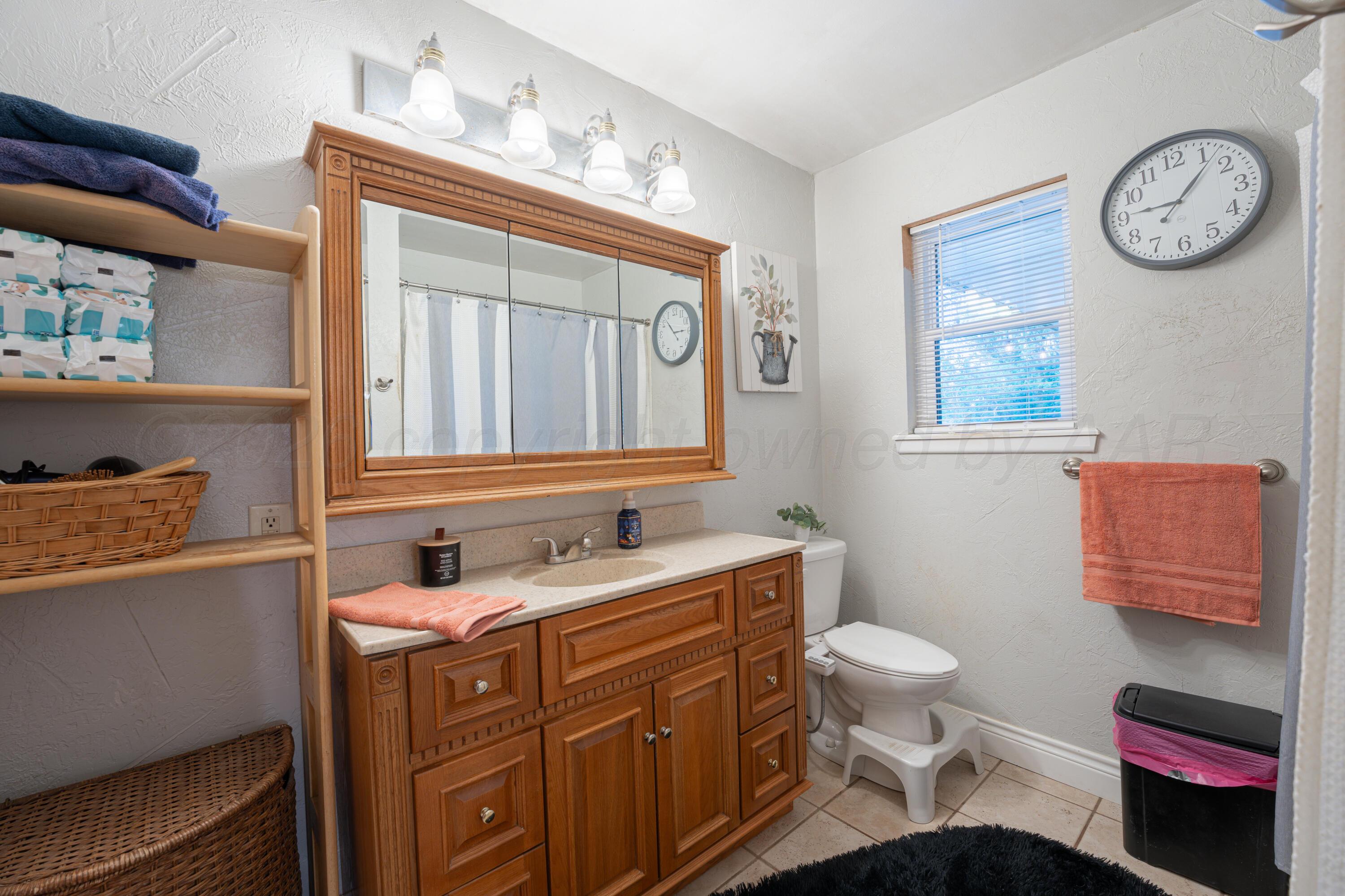 4836 Hillside Road Amarillo, TX 79109 - Photo 18 of 28 a bathroom with a toilet a sink and a mirror