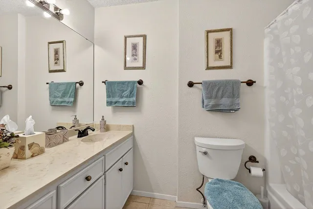 a bathroom with a granite countertop toilet sink and mirror