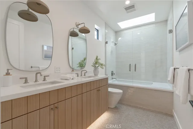 a bathroom with a double vanity sink toilet mirror and bathtub