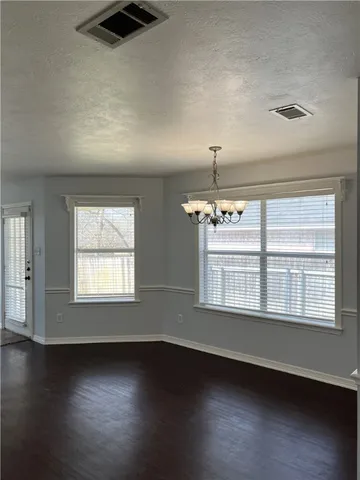 an empty room with wooden floor chandelier fan and windows