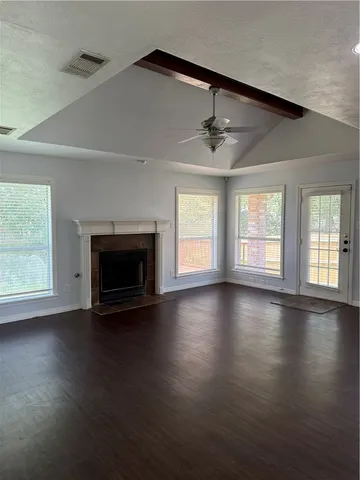an empty room with wooden floor fireplace and windows