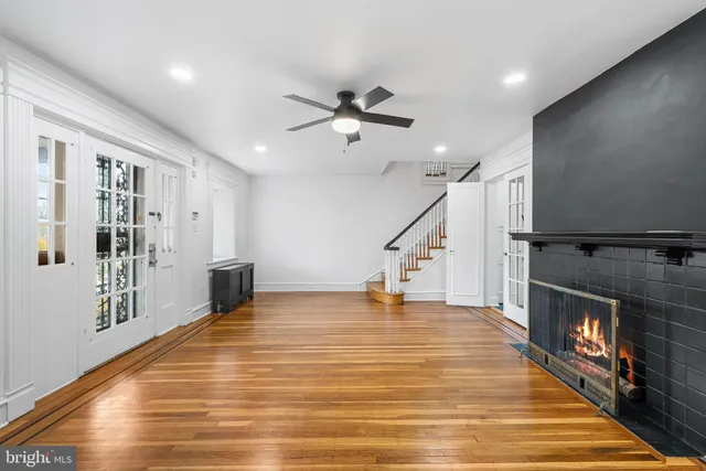 a view of an empty room with wooden floor and a ceiling fan