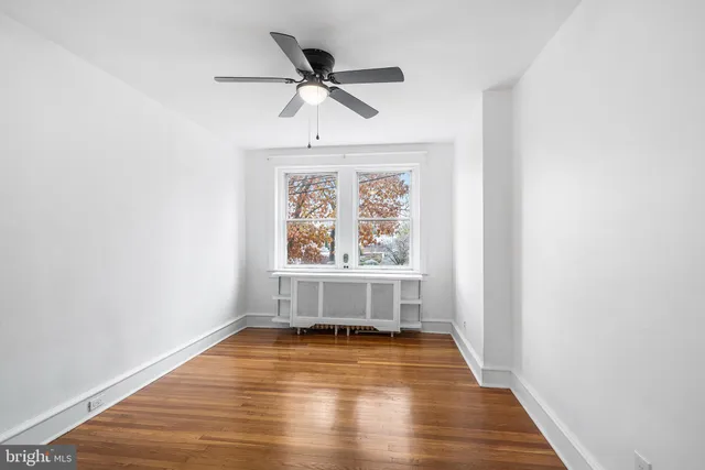a view of empty room with wooden floor and fan