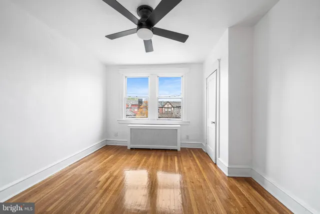 a view of empty room with wooden floor and fan