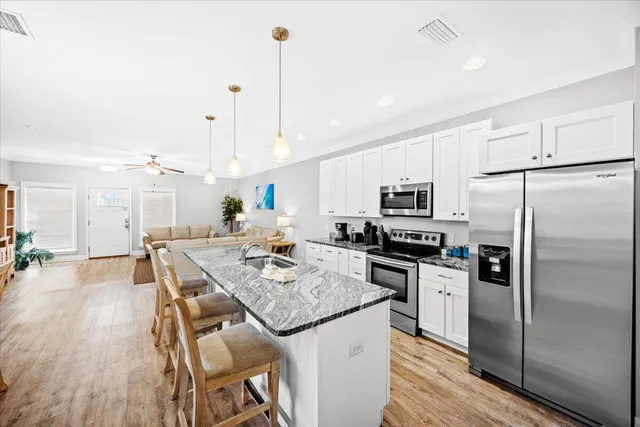 a large kitchen with lots of counter space a sink dishwasher a dining table and chairs with wooden floor