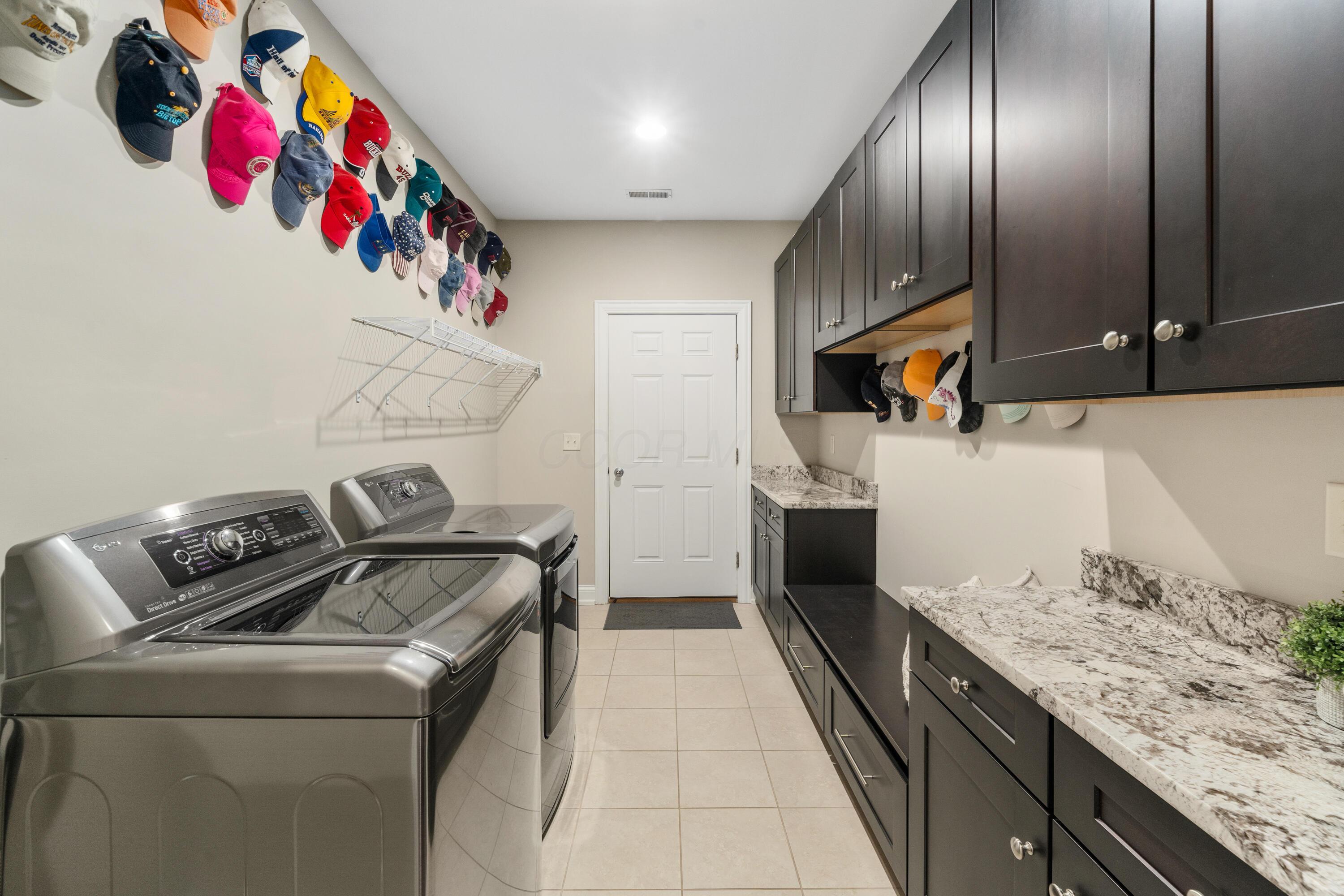4640 Maynard Road Delaware, OH 43015 - Photo 55 of 91 Laundry room featuring light-toned tile flooring, extensive dark wood-finish cabinetry with silver hardware, and light-toned countertop surfaces