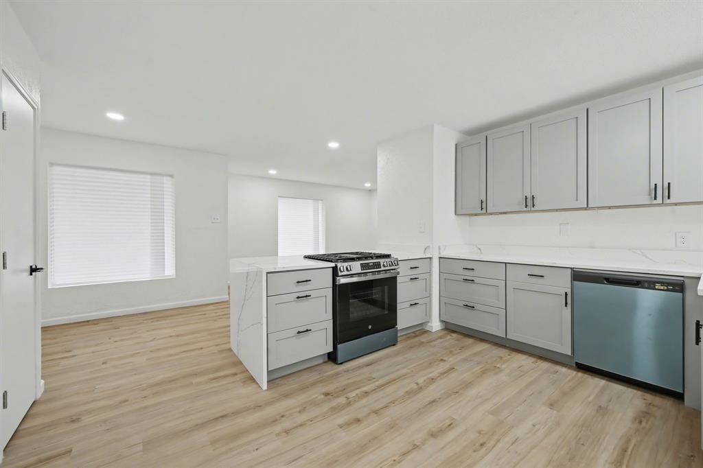 11446 Lippitt Avenue Dallas, TX 75218 - Photo 7 of 26 a kitchen with cabinets wooden floor and stainless steel appliances