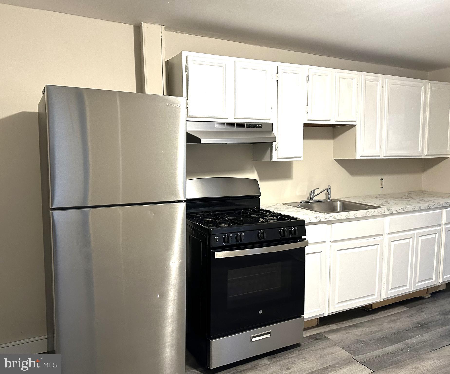 a kitchen with granite countertop white cabinets and refrigerator