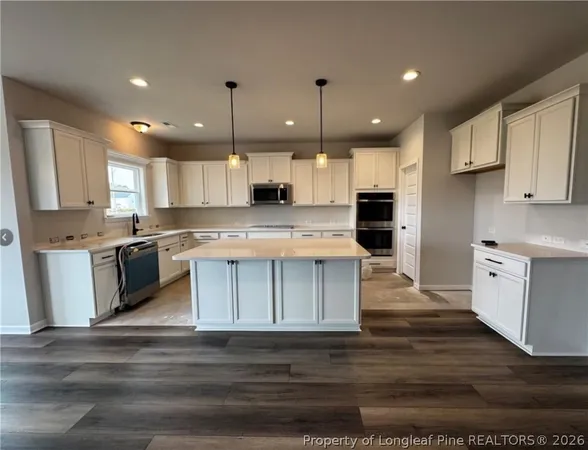 a kitchen with kitchen island granite countertop a sink cabinets and stainless steel appliances