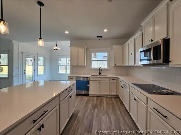 a kitchen with granite countertop a sink a counter space appliances and cabinets
