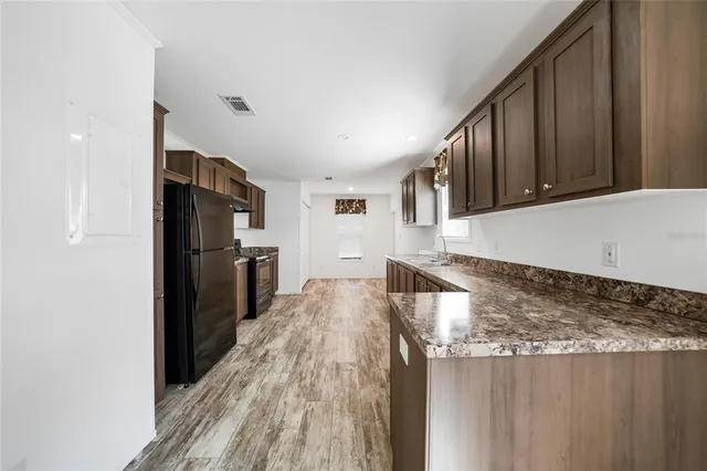 a kitchen with granite countertop a stove cabinets and wooden floor