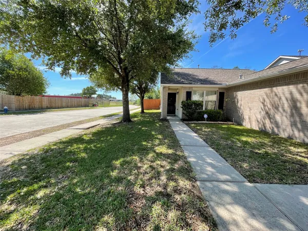 a view of a yard in front of a house with plants and large tree