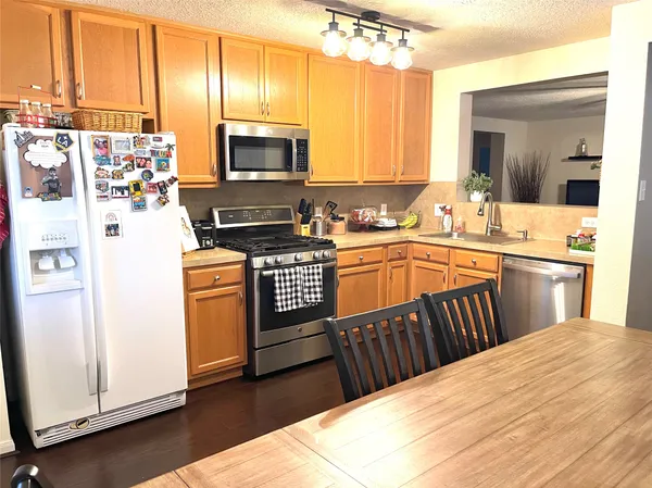 a kitchen with stainless steel appliances granite countertop a stove a sink dishwasher and a microwave oven with white cabinets