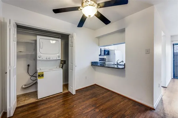 a view of kitchen and empty room with wooden floor