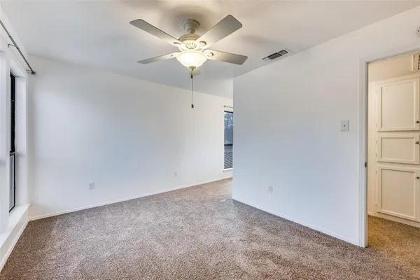 an empty room with a chandelier fan and closet