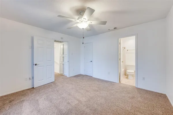 an empty room with chandelier fan and windows