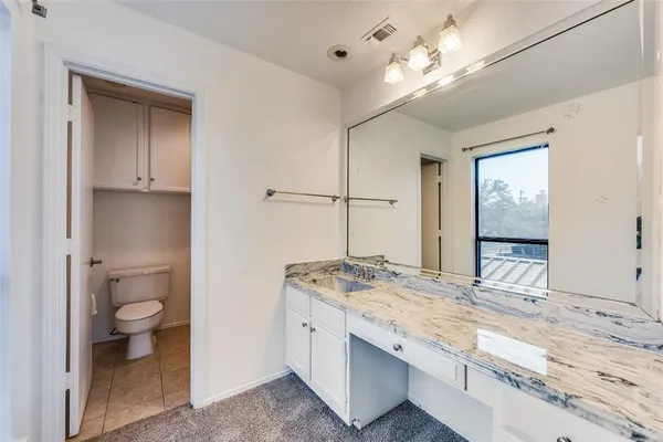 a bathroom with a granite countertop sink a toilet and mirror