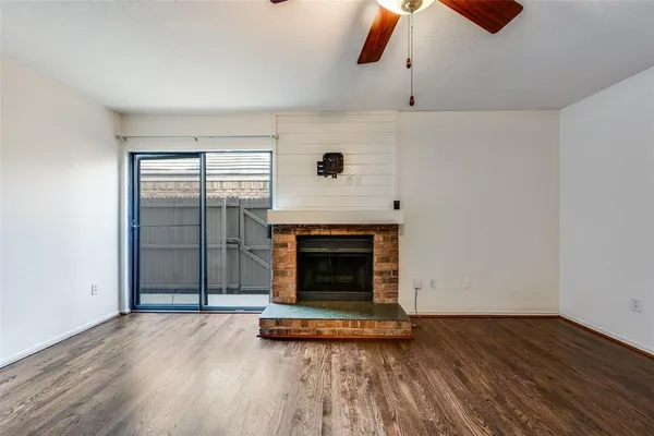 an empty room with wooden floor fireplace and windows