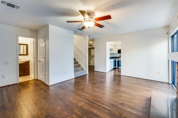 an empty room with wooden floor and a ceiling fan