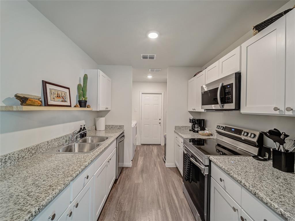 921 West 9th Street Bonham, TX 75418 - Photo 16 of 22 Kitchen with stainless steel appliances, white cabinets, light stone countertops, light wood finished floors, and open shelves