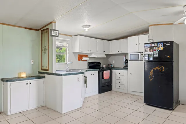 a kitchen with granite countertop white cabinets and refrigerator