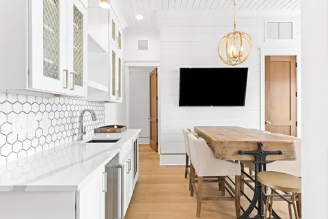 a dining room with wooden floor a chandelier a wooden table and chairs