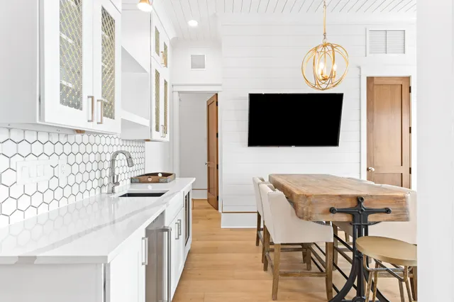 a dining room with wooden floor a chandelier a wooden table and chairs