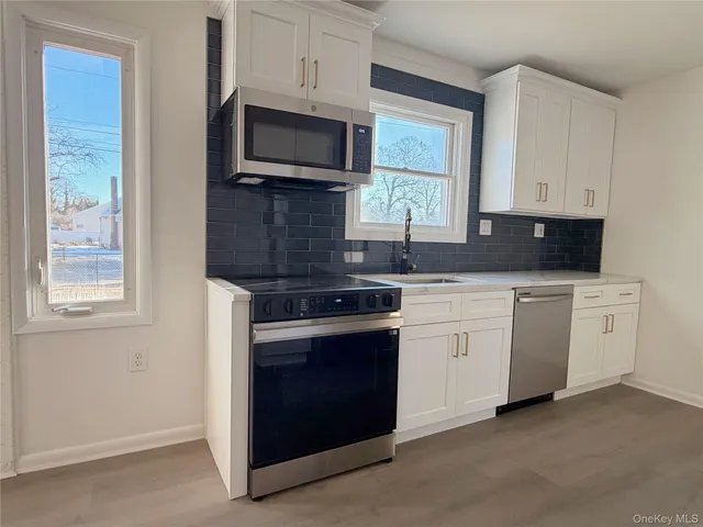 a kitchen with white cabinets and stainless steel appliances