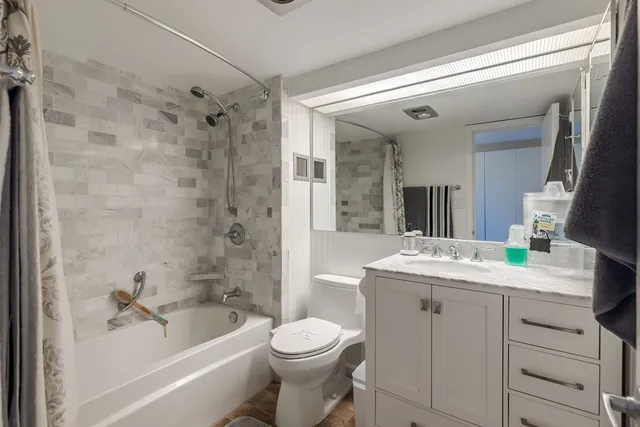 a bathroom with a sink a toilet a mirror a bathtub and shower