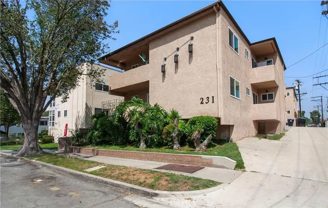 a view of a white house with a big yard and large trees