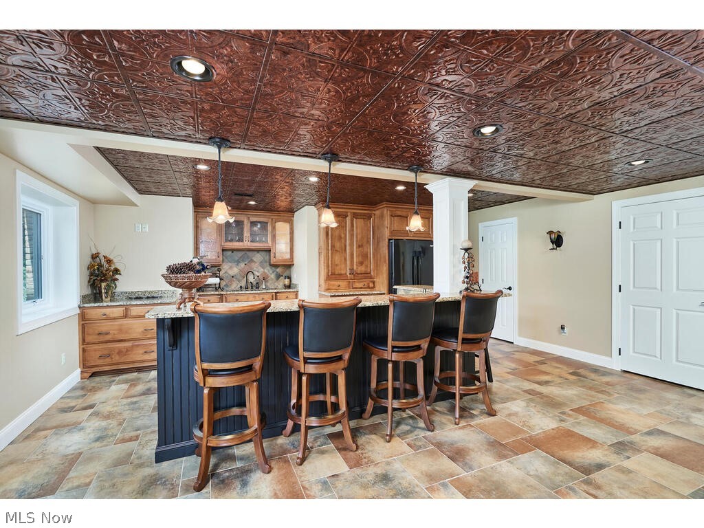 3735 Roberts Ridge Akron, OH 44333 - Photo 24 of 45 Lower Level Kitchen featuring a center island, black fridge, hanging light fixtures, tasteful backsplash, and a kitchen bar