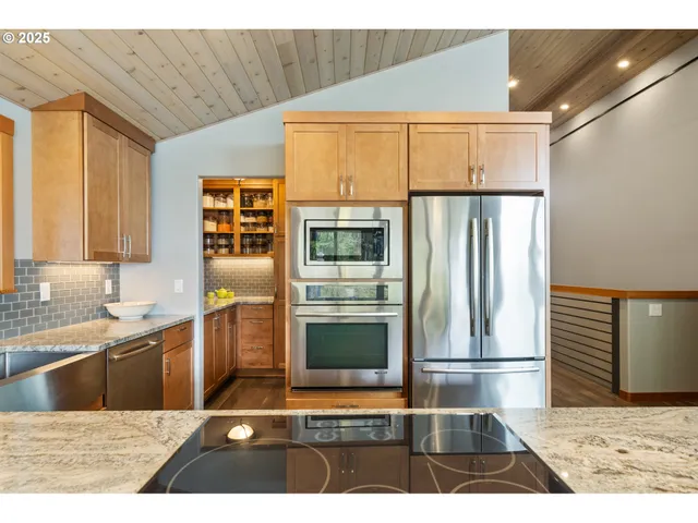a kitchen with stainless steel appliances kitchen island granite countertop a refrigerator and a sink