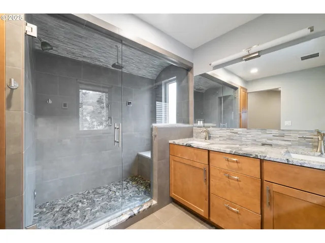 a bathroom with a granite countertop sink a mirror and a shower