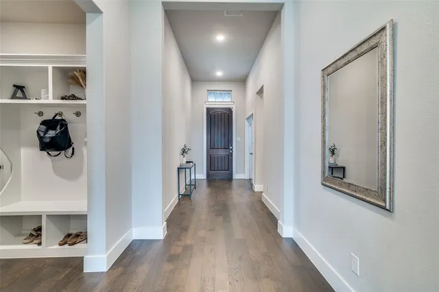 a view of a hallway to a livingroom with wooden floor and furniture