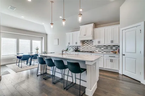 a kitchen with white cabinets and chairs