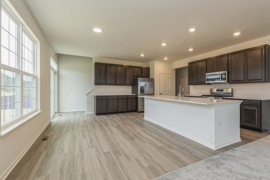 3616 Edelweiss Road Elgin, IL 60124 - Photo 11 of 26 a large kitchen with stainless steel appliances granite countertop a large stove a refrigerator a sink and a microwave oven on the wooden floor next to a large window
