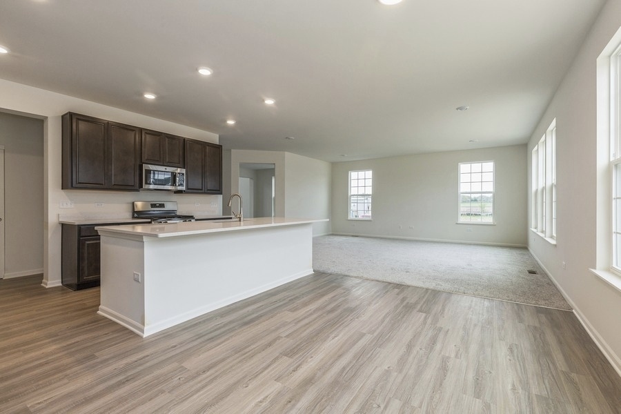 3616 Edelweiss Road Elgin, IL 60124 - Photo 9 of 26 a large kitchen with kitchen island granite countertop a stove top oven a sink with wooden floors and cabinets