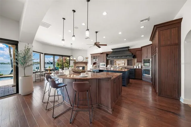 a dining hall with granite countertop a stove a sink dishwasher a dining table and chairs with wooden floor