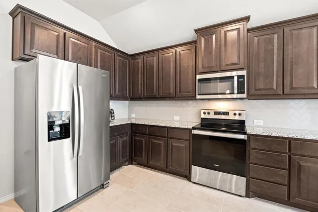 a kitchen with granite countertop wooden cabinets and stainless steel appliances