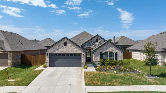 a front view of a house with a garden and mountain view