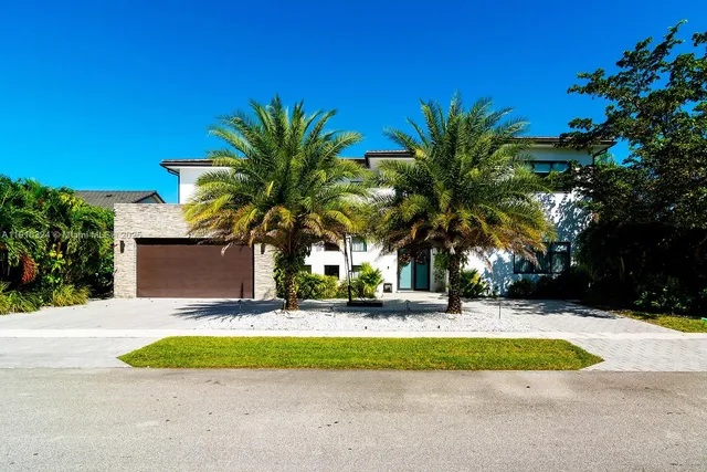 a view of a house with a yard and palm trees