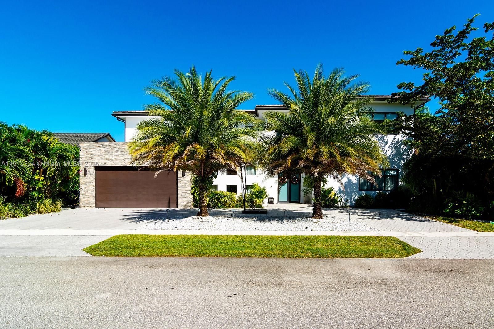a view of a house with a yard and palm trees