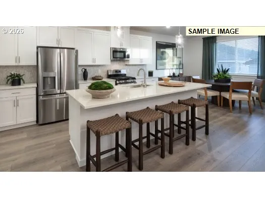 a kitchen with stainless steel appliances kitchen island granite countertop a table chairs and a refrigerator