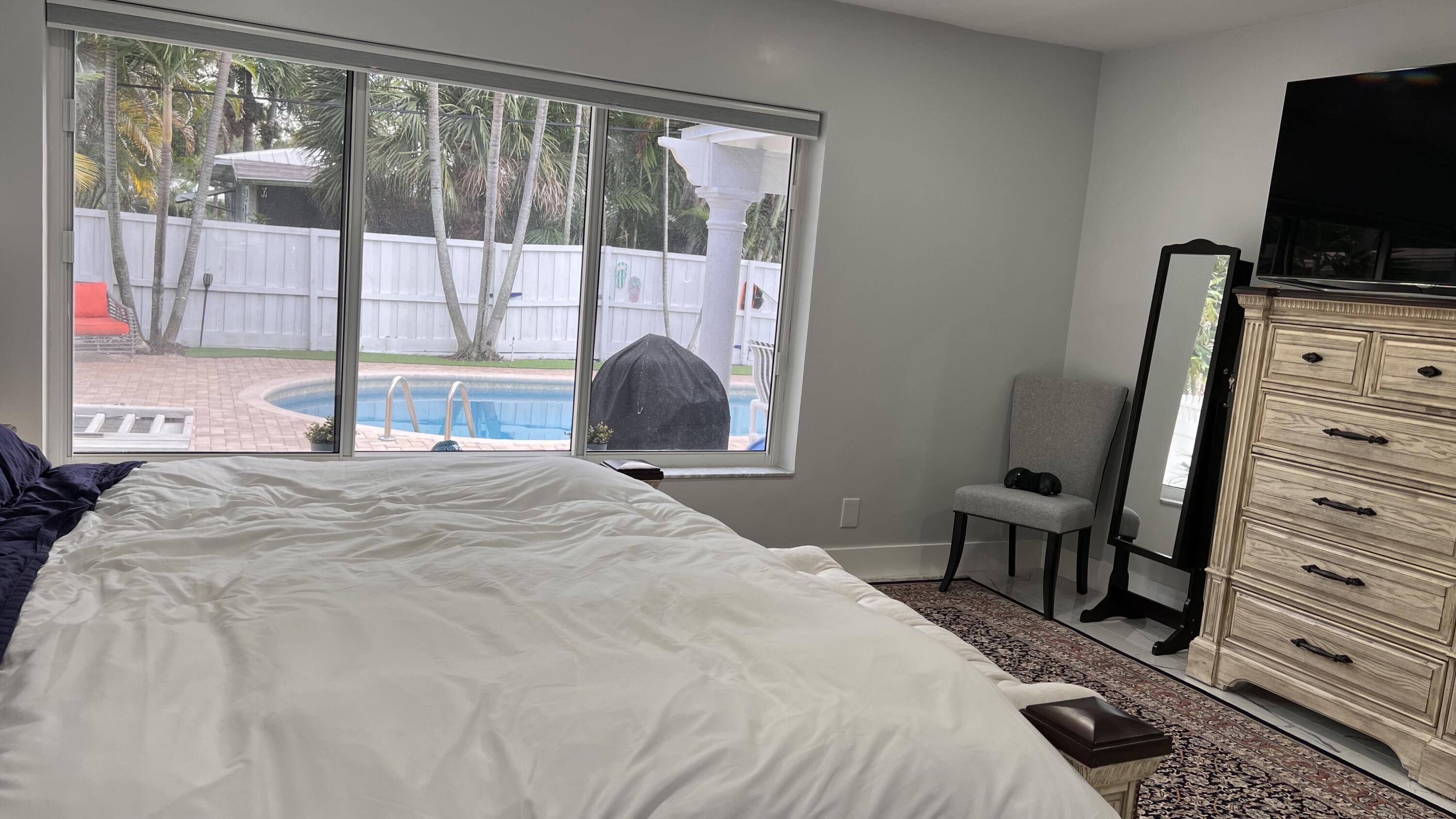 3204 Robbins Road Pompano Beach, FL 33062 - Photo 33 of 37 a bedroom with a bed a flat screen tv and a large window