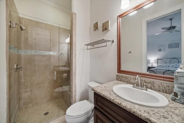 a bathroom with a granite countertop sink a toilet a mirror and shower
