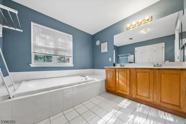 a bathroom with a tub a sink and a large mirror