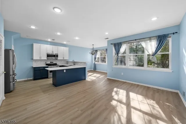 a kitchen with stainless steel appliances kitchen island granite countertop a stove a refrigerator a sink a oven with wooden cabinets and wooden floor