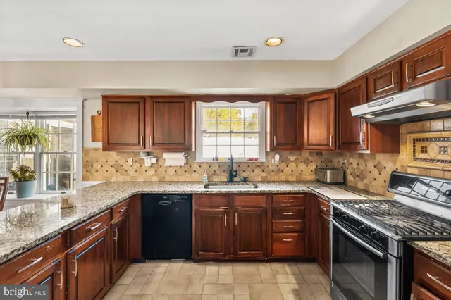 a kitchen with stainless steel appliances granite countertop wooden cabinets stove top oven and sink