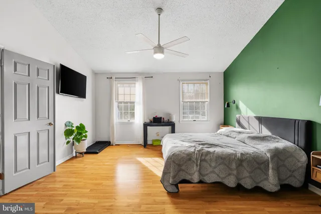 a bedroom with a bed chandelier and a flat tv screen